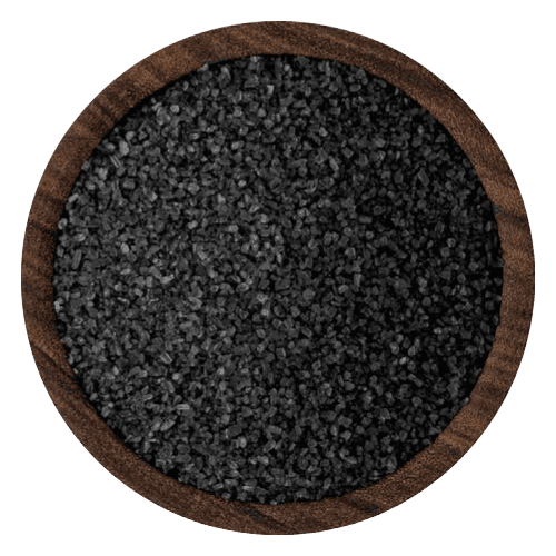 Smooth-textured fine black salt granules spread evenly in a round wooden bowl.